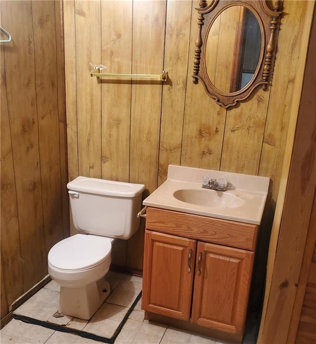 bathroom with tile patterned floors, wood walls, vanity, and toilet