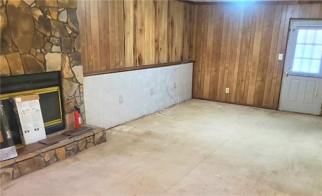 basement with a fireplace, light colored carpet, and wood walls