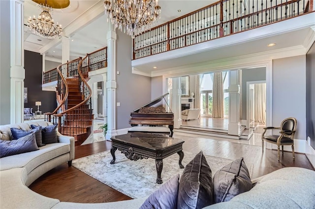 living room with a high ceiling, a chandelier, hardwood / wood-style flooring, and crown molding