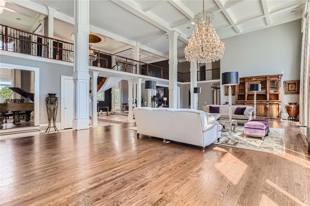 9620 Cedar Grove Rd, Chattahoochee Hills, GA 30213 - living room featuring a towering ceiling, ornate columns, wood finished floors, a chandelier, and beamed ceiling