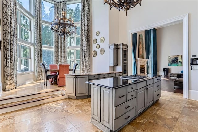 9620 Cedar Grove Rd, Chattahoochee Hills, GA 30213 - kitchen with gray cabinetry, a chandelier, a center island, a towering ceiling, and healthy amount of natural light
