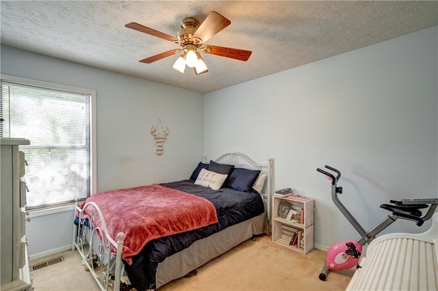 carpeted bedroom with multiple windows, ceiling fan, and a textured ceiling