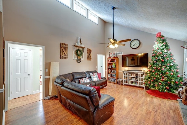 living room with wood-type flooring, a textured ceiling, high vaulted ceiling, and ceiling fan