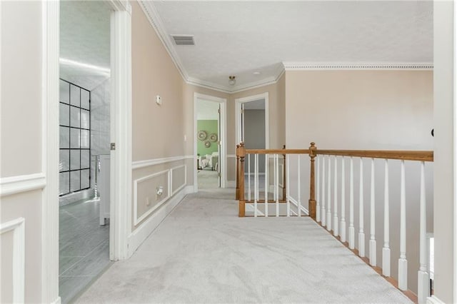 hallway with visible vents, a decorative wall, and ornamental molding