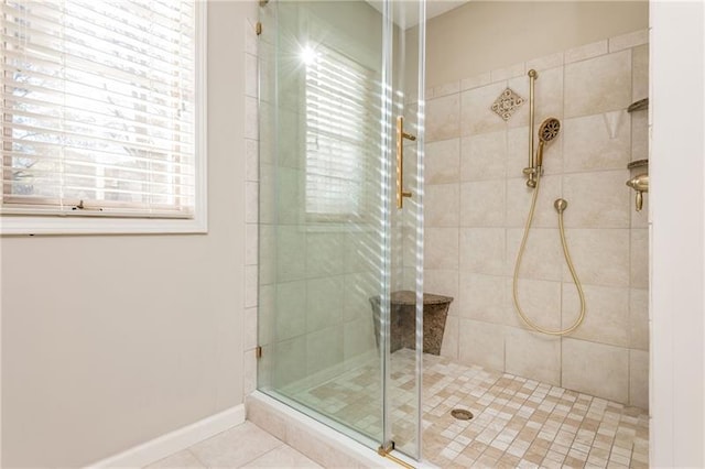 full bath featuring tile patterned floors, baseboards, and a stall shower