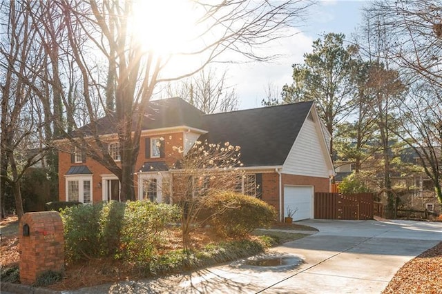 colonial home with brick siding, an attached garage, driveway, and fence