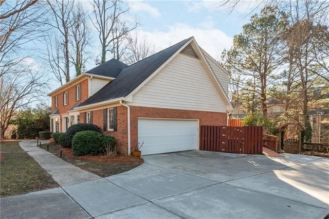 view of side of property featuring concrete driveway, a garage, fence, and brick siding