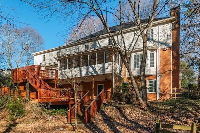 rear view of house with stairway, a deck, a chimney, and a sunroom