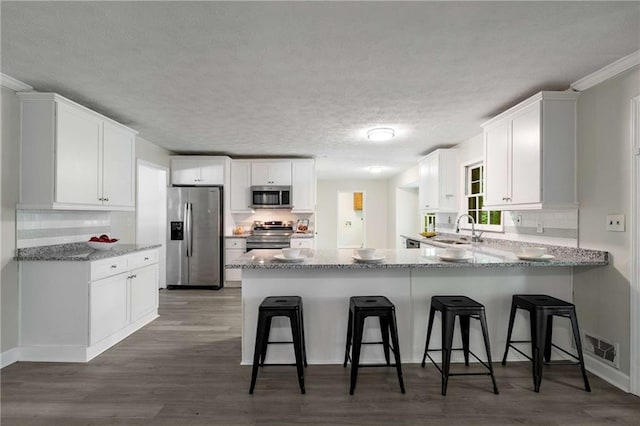 2694 Hickory Valley Dr, Snellville, GA 30078 - kitchen featuring stainless steel appliances, a peninsula, a textured ceiling, and white cabinets