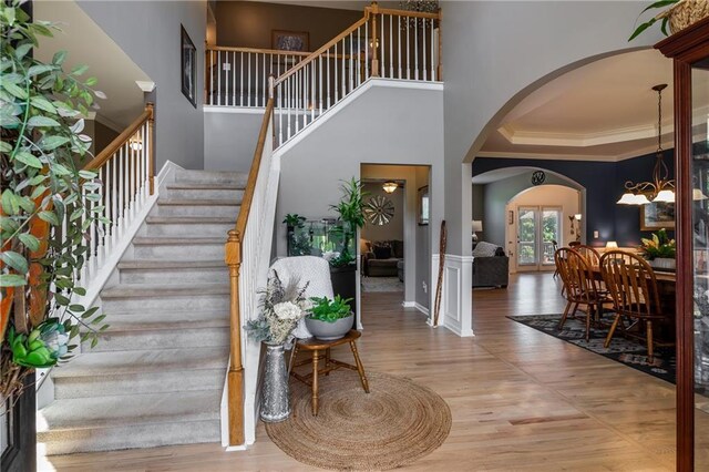 foyer entrance with crown molding, light hardwood / wood-style floors, and a high ceiling