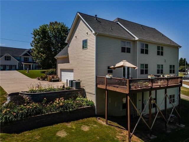 back of property featuring a garage, a wooden deck, a yard, and central air condition unit