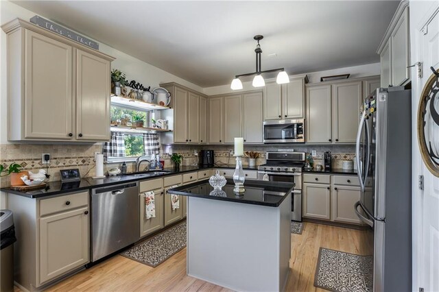 kitchen with appliances with stainless steel finishes, pendant lighting, sink, gray cabinetry, and a center island