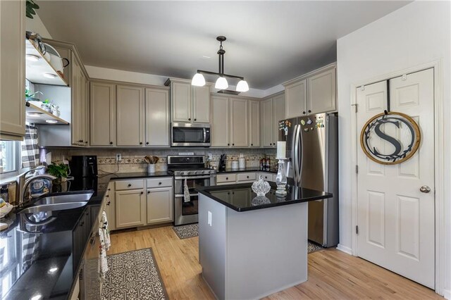 kitchen featuring stainless steel appliances, a center island, sink, and light wood-type flooring