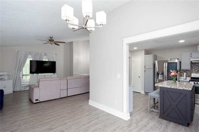 kitchen with stainless steel appliances, vaulted ceiling, ceiling fan, light wood finished floors, and backsplash
