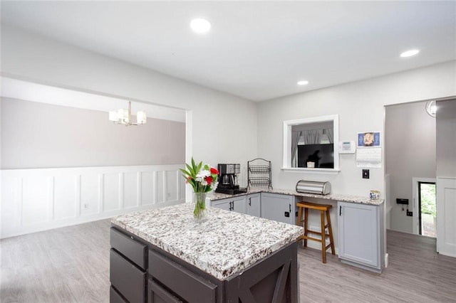 kitchen featuring light wood-style flooring, light stone countertops, a chandelier, gray cabinetry, and recessed lighting