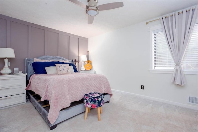 bedroom with light carpet, baseboards, a decorative wall, and ceiling fan