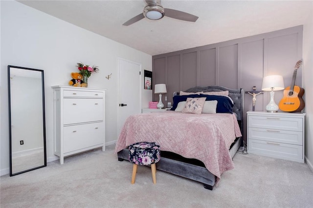bedroom featuring a decorative wall, light colored carpet, and ceiling fan