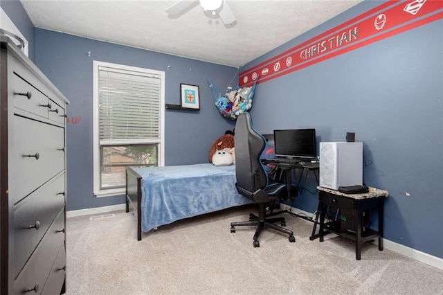 carpeted bedroom with baseboards, ceiling fan, and a desk