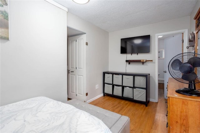 bedroom featuring light wood-style floors, a textured ceiling, and baseboards