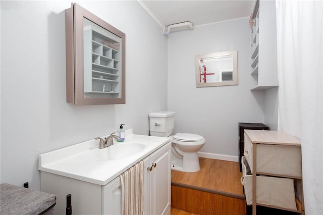 bathroom with vanity, toilet, wood finished floors, and baseboards