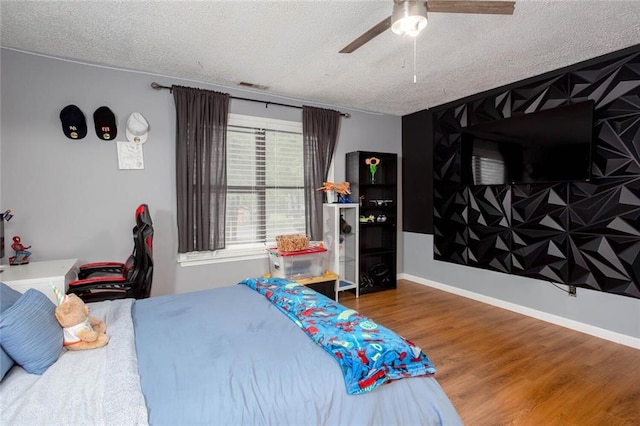 bedroom with a textured ceiling, wood finished floors, and a ceiling fan