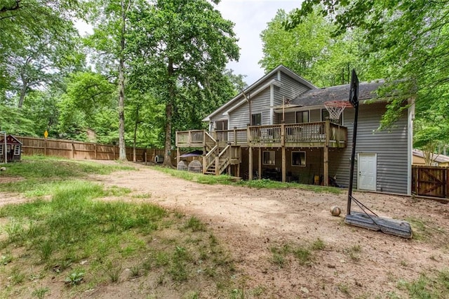 back of property with a wooden deck, a fenced backyard, and stairs