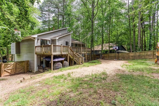 rear view of house featuring a deck, stairway, a fenced backyard, and a gate