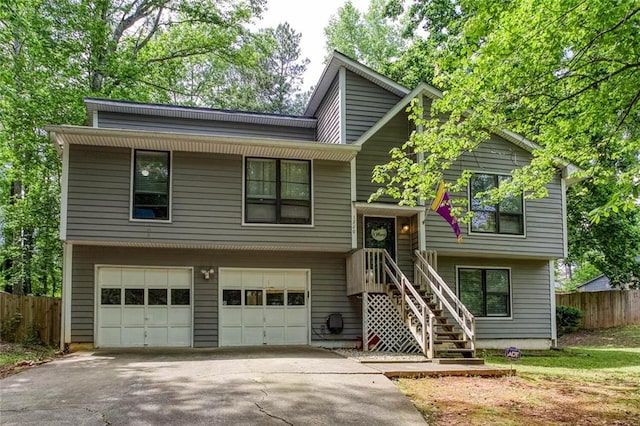 split foyer home with a garage, fence, and asphalt driveway