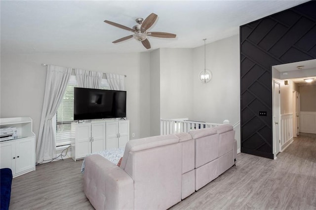 living room with lofted ceiling, a ceiling fan, light wood finished floors, and a decorative wall