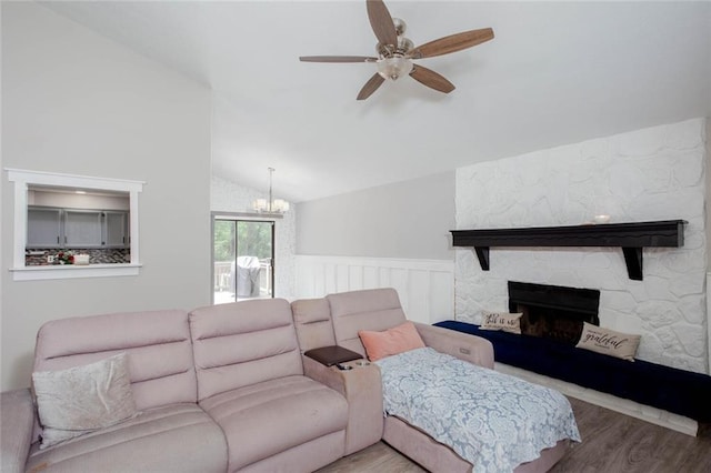 living area with wood finished floors, vaulted ceiling, a ceiling fan, a chandelier, and a wainscoted wall