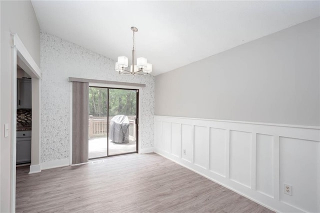 unfurnished room featuring a chandelier, wood finished floors, and a wainscoted wall
