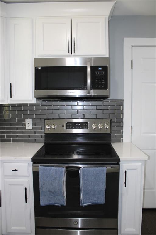 kitchen featuring decorative backsplash, white cabinets, and stainless steel appliances