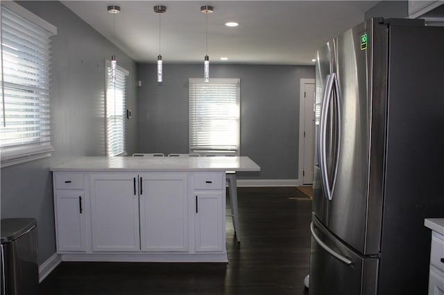 kitchen featuring dark hardwood / wood-style floors, pendant lighting, kitchen peninsula, stainless steel refrigerator, and white cabinets