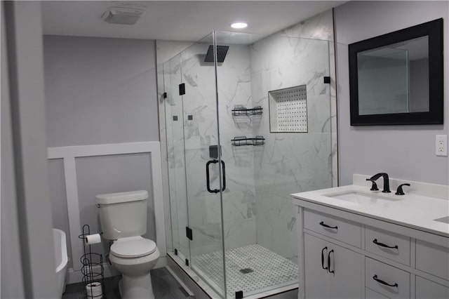 bathroom with walk in shower, vanity, and toilet