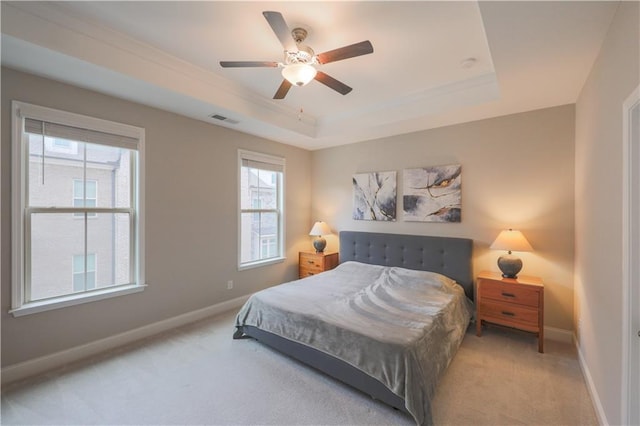 bedroom featuring a tray ceiling, light colored carpet, visible vents, and baseboards