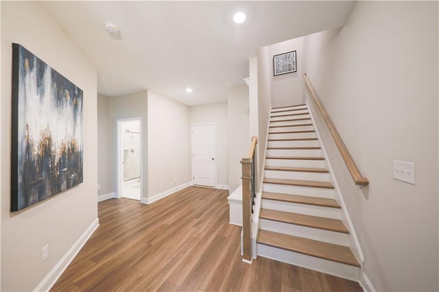 staircase featuring baseboards, wood finished floors, and recessed lighting