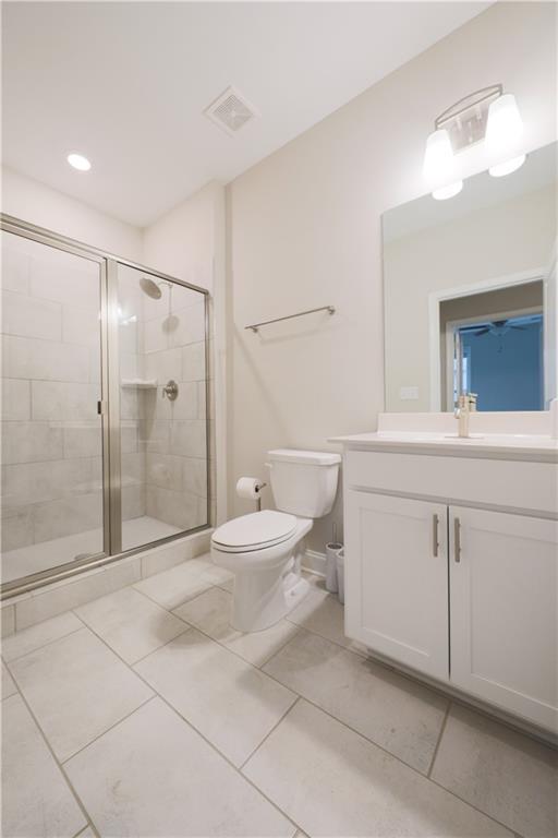 bathroom featuring toilet, a stall shower, visible vents, and vanity