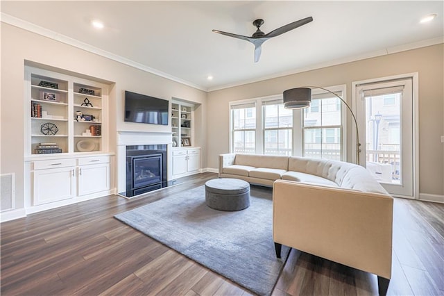 living area featuring a fireplace with flush hearth, dark wood-style flooring, crown molding, and baseboards