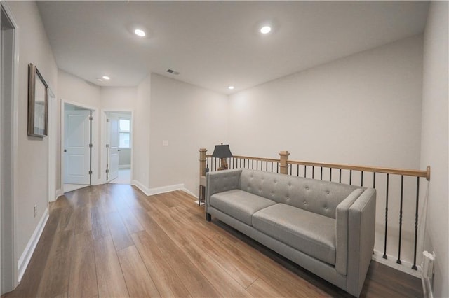 living room with recessed lighting, visible vents, baseboards, and wood finished floors