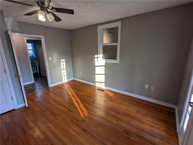 unfurnished bedroom featuring dark hardwood / wood-style flooring, ceiling fan, and a textured ceiling