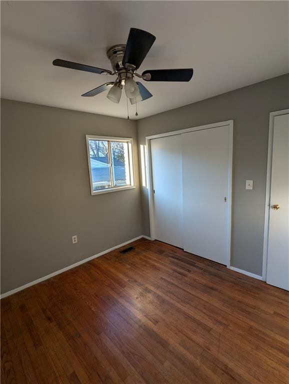 unfurnished bedroom featuring ceiling fan, dark hardwood / wood-style floors, and a closet