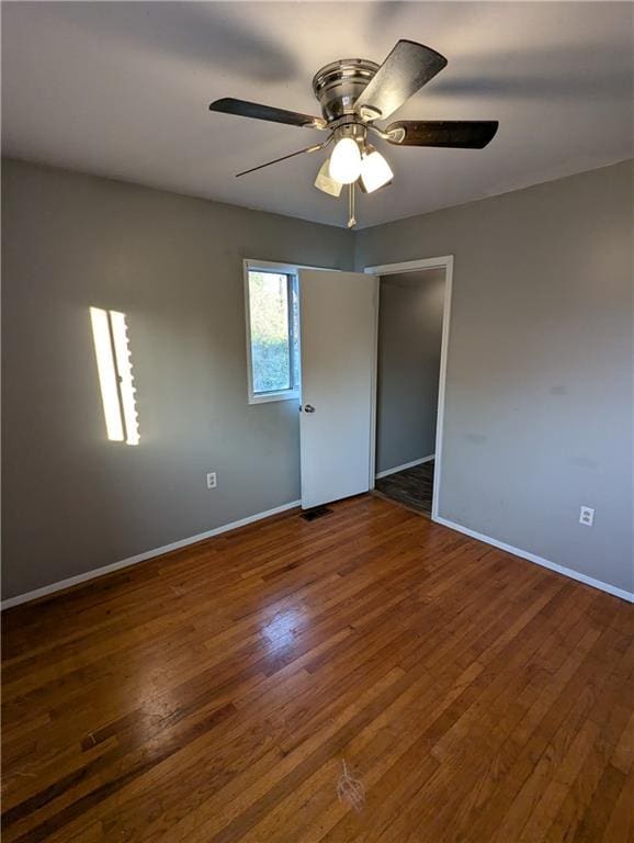 unfurnished room featuring dark wood-type flooring and ceiling fan