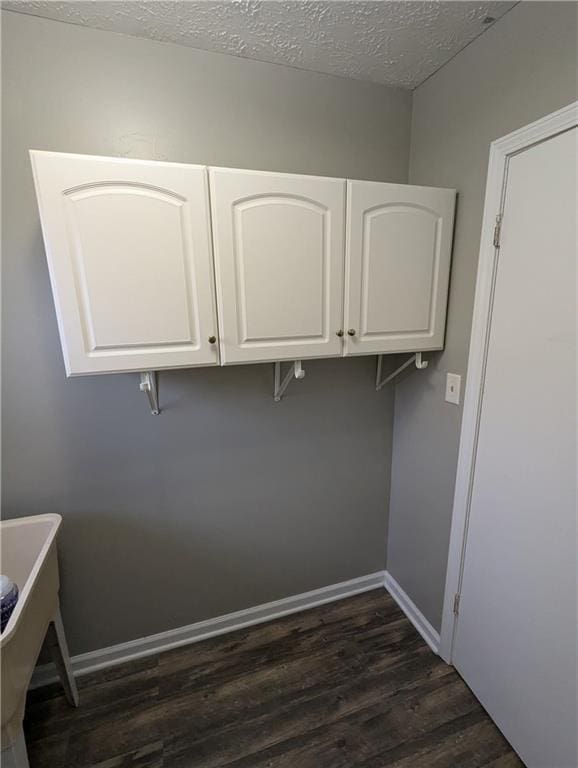 laundry area with dark hardwood / wood-style floors and a textured ceiling