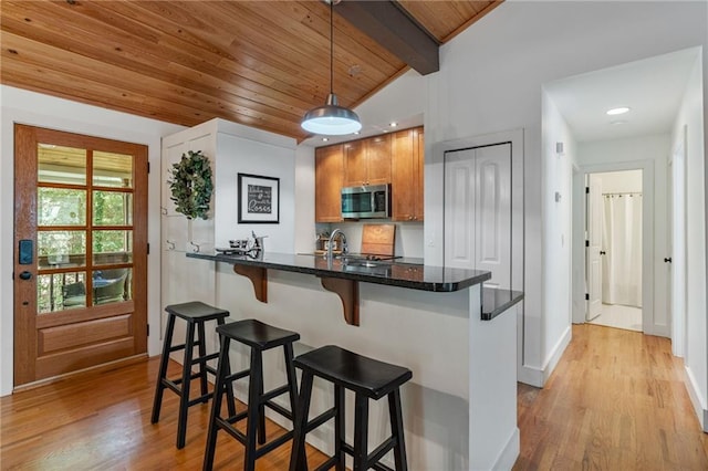 7875 Robin Rd, Cumming, GA 30041 - kitchen with stainless steel microwave, wooden ceiling, a breakfast bar area, light wood-style flooring, and decorative light fixtures