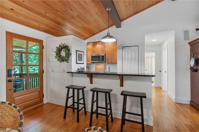7875 Robin Rd, Cumming, GA 30041 - kitchen with stainless steel microwave, a breakfast bar area, light wood finished floors, baseboards, and decorative light fixtures
