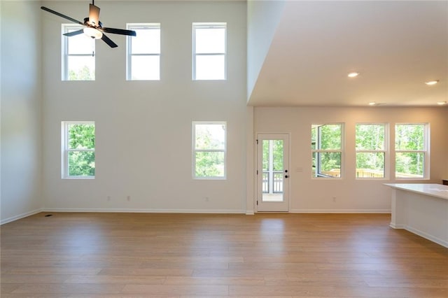 296 River Run Dr, Dallas, GA 30132 - unfurnished living room with baseboards, light wood-type flooring, ceiling fan, a high ceiling, and recessed lighting