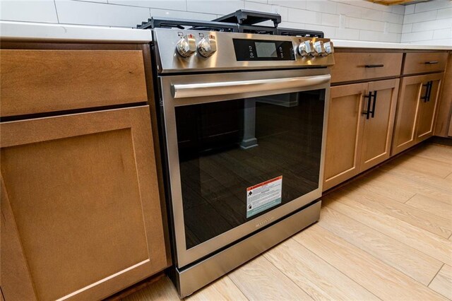 296 River Run Dr, Dallas, GA 30132 - detailed view of light wood-type flooring, brown cabinetry, gas range, and light countertops