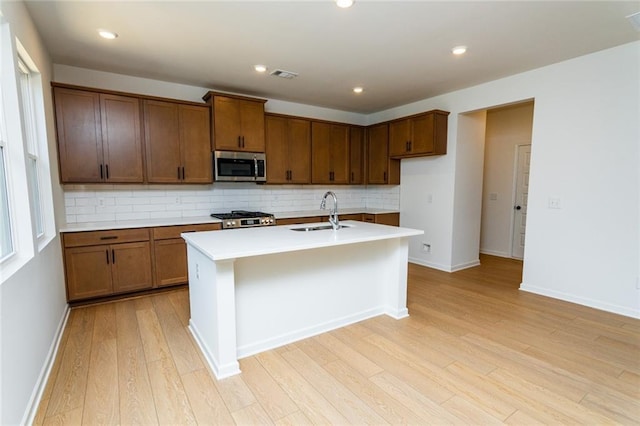 296 River Run Dr, Dallas, GA 30132 - kitchen with stainless steel microwave, a sink, stove, light wood-style flooring, and decorative backsplash