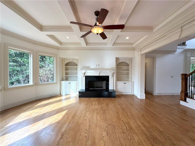 unfurnished living room with a fireplace with raised hearth, baseboards, built in features, stairs, and light wood-style flooring