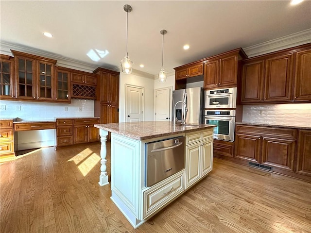 kitchen with a warming drawer, ornamental molding, a sink, appliances with stainless steel finishes, and light wood finished floors